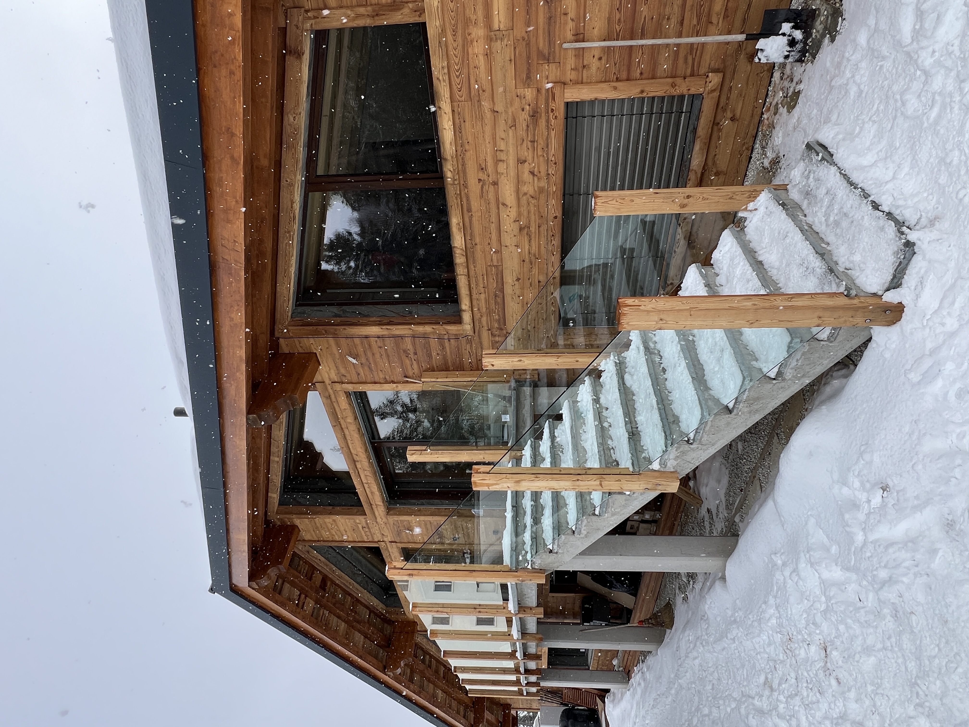 Escalier extérieur avec garde-corps en verre trempé pour chalet en bois.