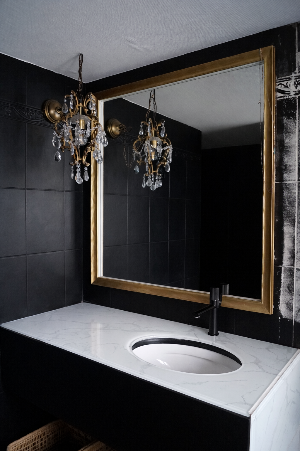 Miroir encadré doré sur mesure dans salle de bain élégante avec carrelage noir et vasque en marbre blanc.