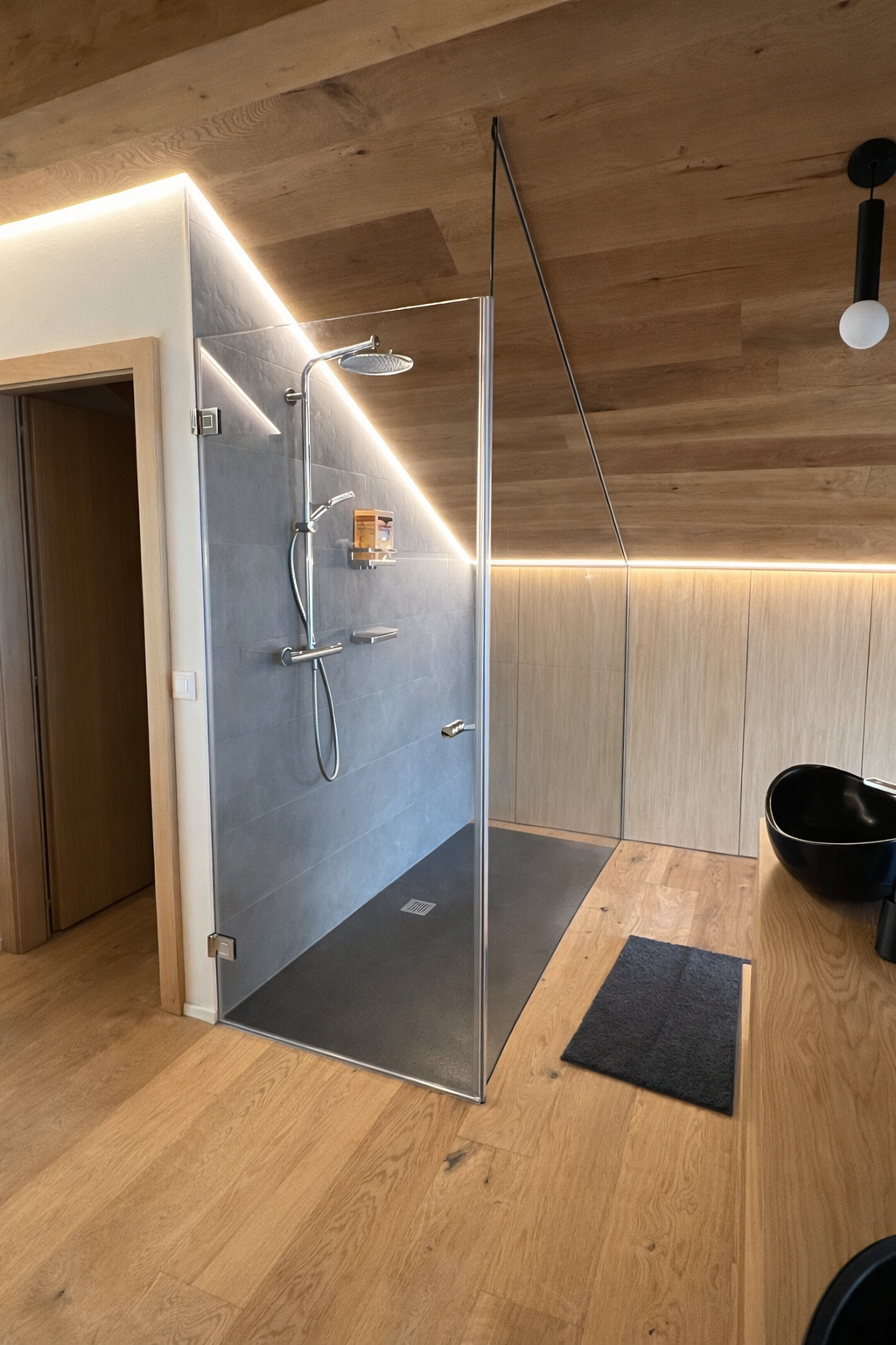 Paroi de douche en verre sur mesure sous plafond incliné avec éclairage LED intégré.